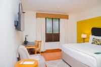 チナンデガにあるHotel Los Portalesのベッドと机と窓のある寝室