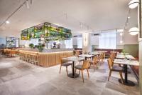Un restaurante con mesas y sillas y un bar. en Holiday Inn Melbourne Bourke Street Mall by IHG, en Melbourne