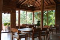 a dining room with tables and chairs and windows at Nunu Bali Eco Friendly Retreat in Canggu