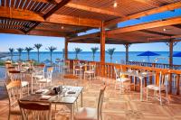 un ristorante con tavoli e sedie con l'oceano sullo sfondo di Pickalbatros Villaggio Aqua Park - Portofino Marsa Alam a Marsa Alam