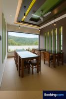 uma sala de jantar com mesas e cadeiras e uma grande janela em Rosa Mystica Hotels & Resorts em Anachal