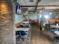een eetkamer met tafels en stoelen en een bakstenen muur bij Big Horn motor Inn in Grande Cache