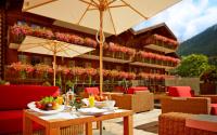 a table with food and an umbrella on a patio at Grand Hotel Zermatterhof in Zermatt