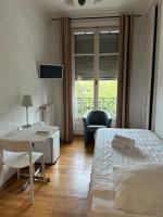 Un dormitorio con una cama, un escritorio y una silla. en Hotel des Tourelles, en Ginebra