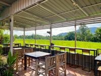 a patio with tables and chairs and a view of a field at TheOrientalVillage in Ban Pao Sam Kha
