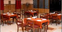 a dining room with wooden tables and chairs at Utsav Hotels and Banquets Bolpur in Bolpur