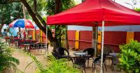 a group of tables and chairs under a red umbrella at Utsav Hotels and Banquets Bolpur in Bolpur