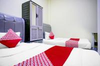 Una habitación con dos camas con sábanas rojas y blancas. en Hotel O Balige City Near Tugu Juara Monang, en Balige