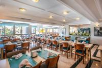 a dining room with tables and chairs and windows at Palmin Hotel in Kusadası