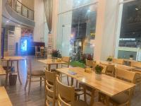 ニャチャンにあるLanxy Hotel Nha Trangの木製のテーブルと椅子と窓のあるレストラン