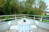 a white table with chairs and a vase of flowers on a balcony at Apartman Tramontana in Opatija