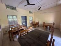 a dining room with wooden tables and chairs at New Kaziranga Cottage in Kāziranga