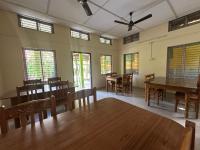 a dining room with tables and chairs and windows at New Kaziranga Cottage in Kāziranga