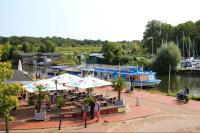 ein Yachthafen mit Tischen und Sonnenschirmen und einem Boot in der Unterkunft Studio-Apartment mit Balkon in Plau am See fußläufig zum Strand und zur Altstadt in Plau am See