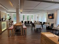 ヴォルムスにあるHotel am Schlossparkのテーブルと椅子と窓のあるダイニングルーム