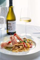 un plato de pasta con camarones y una botella de vino en Excelsior Palace Hotel, en Taormina