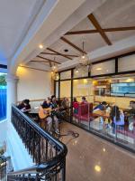 プエルト・プリンセサにあるHola Hostel Puerto Princesaのバルコニーに座ってギターを弾いている人々のグループ