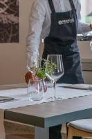 Una persona en una cocina con dos copas de vino sobre una mesa. en Hub Hotel, en Gubbio