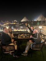 a group of people sitting at a table with pyramids in the background at Kayan Pyramids View in Cairo