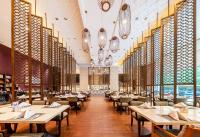 uma sala de jantar com mesas, cadeiras e janelas em Wanda Realm Langfang em Langfang