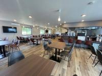 Un restaurante con mesas y sillas y una cocina. en Joy Park Hotel 種子島, en Nishinoomote