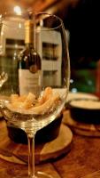 a wine glass sitting on a table with a bottle of wine at Luau Hotel in Guajiru