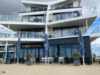 een gebouw met tafels en stoelen en blauwe parasols bij Apartment Hygge mit Ostseeblick in Wendtorf