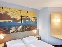 Un dormitorio con un póster de un tren. en B&amp;B Hotel Saarbrücken-Hbf, en Saarbrücken