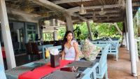 a woman sitting at a table in a restaurant at Nataya Round House Coral Bay Resort in Kampot