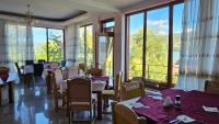 ein Restaurant mit Tischen und Stühlen und großen Fenstern in der Unterkunft Pensiunea Delfinul in Văleni