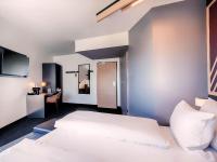 フレッヒェンにあるB&amp;B HOTEL Köln-Frechenの白いベッドと机のある寝室