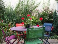 einen Tisch und Stühle in einem Garten mit roten Blumen in der Unterkunft Bed and Breakfast Le patio in Montigny-lès-Metz