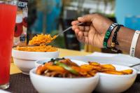 una persona che mangia cibo su un tavolo con ciotole di cibo di Les Chambres in Nakasero, Kampala By BoB a Kampala