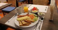 une assiette de petit-déjeuner sur une table avec du jus d'orange dans l'établissement Journeyhub Sukhumvit 26, Bangkok - Formerly St James Hotel, à Bangkok