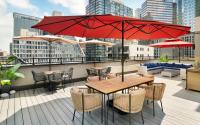 Un patio con mesas y sillas y una sombrilla roja. en EVEN Hotel Long Island City - New York by IHG, en Long Island City