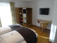 a bedroom with a bed and a desk and a television at Pension Rosenhof in Brixen im Thale