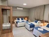 una habitación de hotel con dos camas y una silla en Hotel Mato Grosso Inn, en Cuiabá