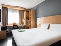Una habitación de hotel con una gran cama blanca y una silla. en ibis Genève Centre Gare, en Ginebra