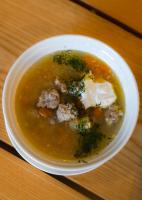 Un tazón blanco de sopa con albóndigas. en Gusta Imperial, 