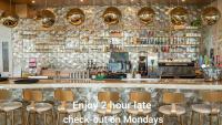Un bar con una pared de piedra y taburetes dorados. en The Feather&#39;s Hotel Newquay, en Newquay
