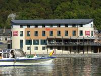 a boat in the water in front of a building at ibis Dinant Centre in Dinant