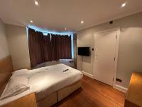 a bedroom with a large white bed and a television at Cavendish Annexe in High Wycombe