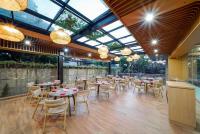 um restaurante com mesas, cadeiras e janelas em Truntum Cihampelas em Bandung