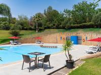 una piscina con mesa, sillas y sombrillas en Ibis Meknès, en Meknès
