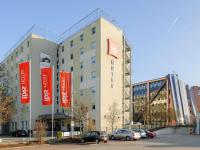 Un gran edificio con coches aparcados en un estacionamiento. en ibis Stuttgart Airport Messe, en Leinfelden-Echterdingen