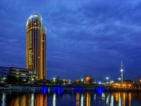 un edificio alto junto a un río por la noche en Pullman Linyi Lushang, en Linyi