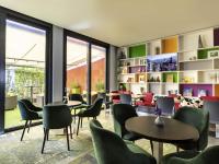 una sala de espera con mesas, sillas y ventanas en ibis Styles Karlsruhe Ettlingen, en Ettlingen