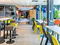 a restaurant with yellow tables and chairs at ibis budget Strasbourg Sud Illkirch in Geispolsheim