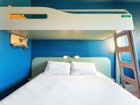 una cama en una habitación con una pared azul en ibis budget Mâcon Nord, en Mâcon