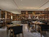 a restaurant with tables and chairs and a kitchen at Novotel Chennai Chamiers Road in Chennai